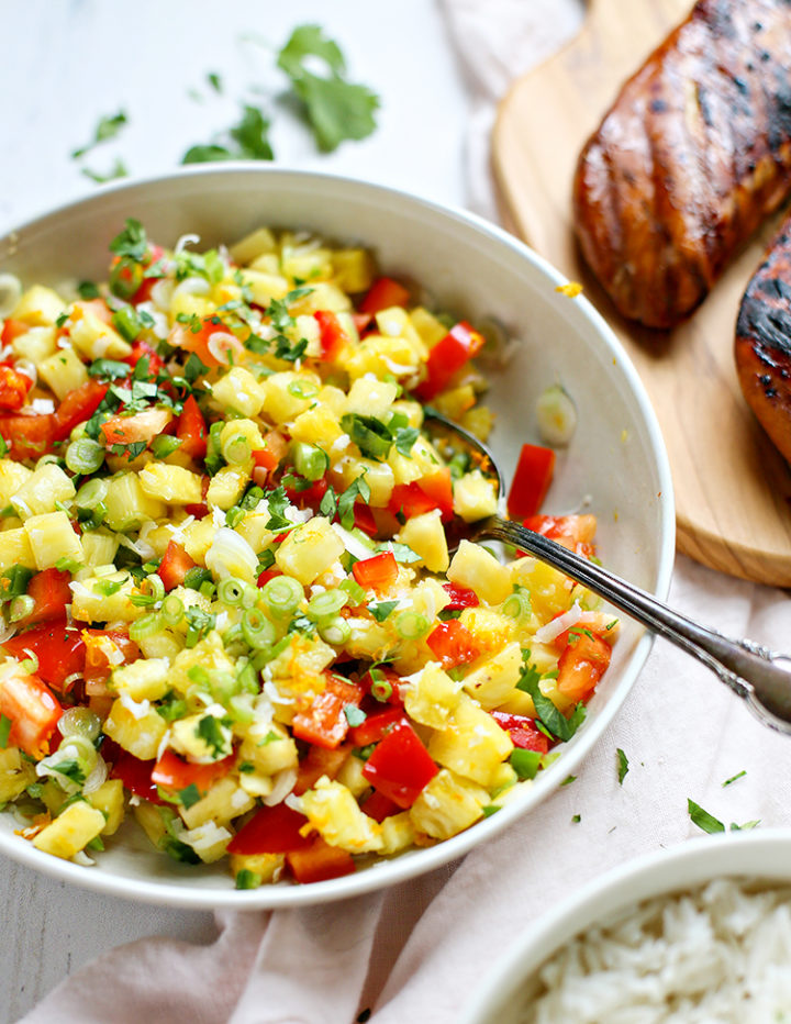 pineapple salsa in a white bowl next to grilled chicken for an idea for taco tuesday taco night