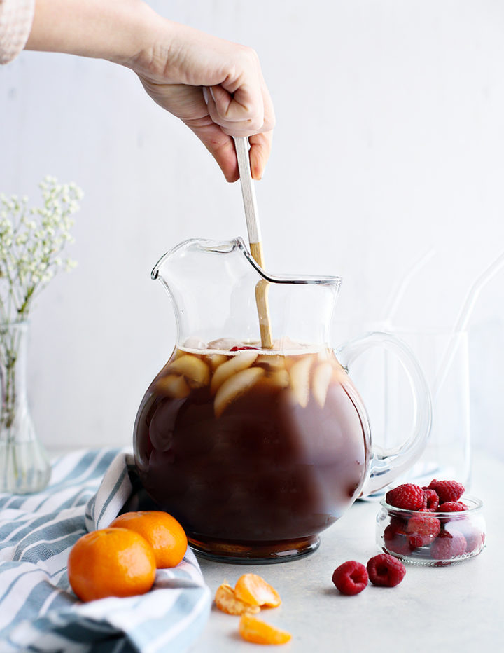 photo of a woman stirring a pitcher of homemade raspberry iced tea