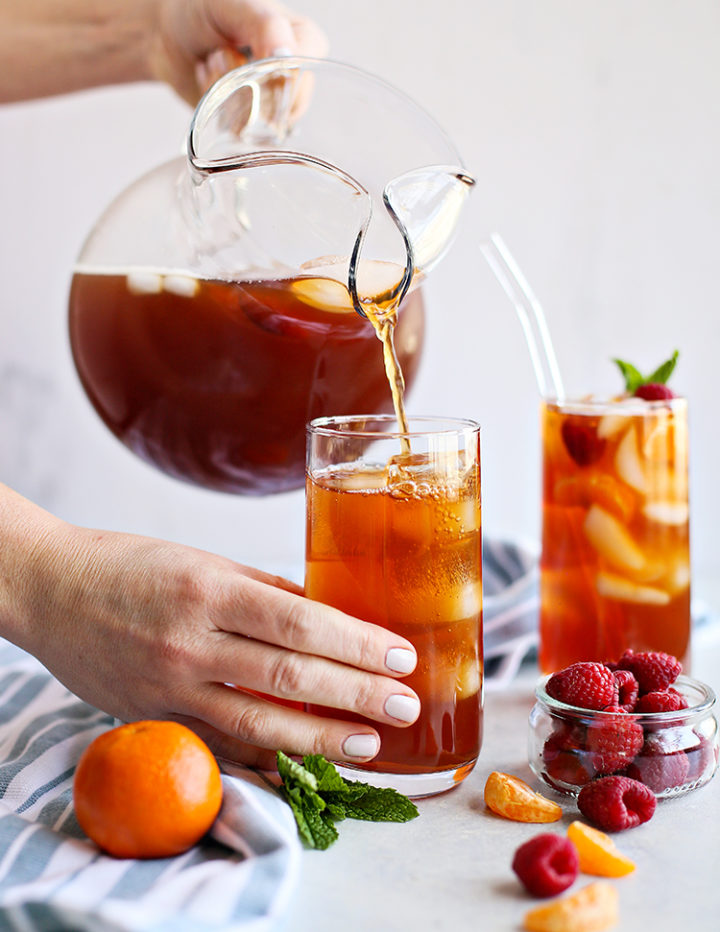 photo of a woman filling a glass of ice with homemade raspberry iced tea
