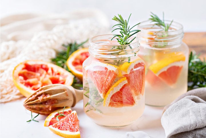 photo of a vodka tonic cocktail with a citrus reamer and juiced grapefruit halves