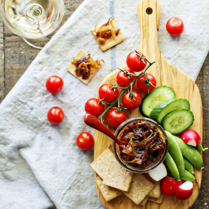 photo of a jar of caramelized onions with vegetables and crackers on a cutting board