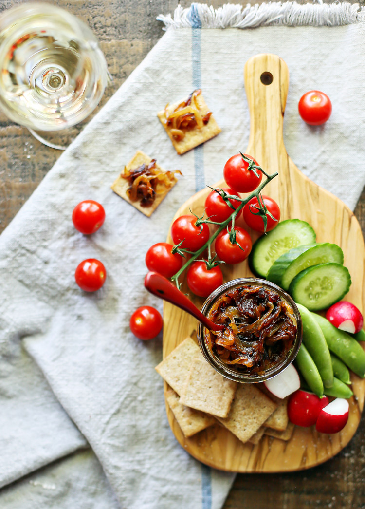 photo of a jar of caramelized onions with vegetables and crackers on a cutting board