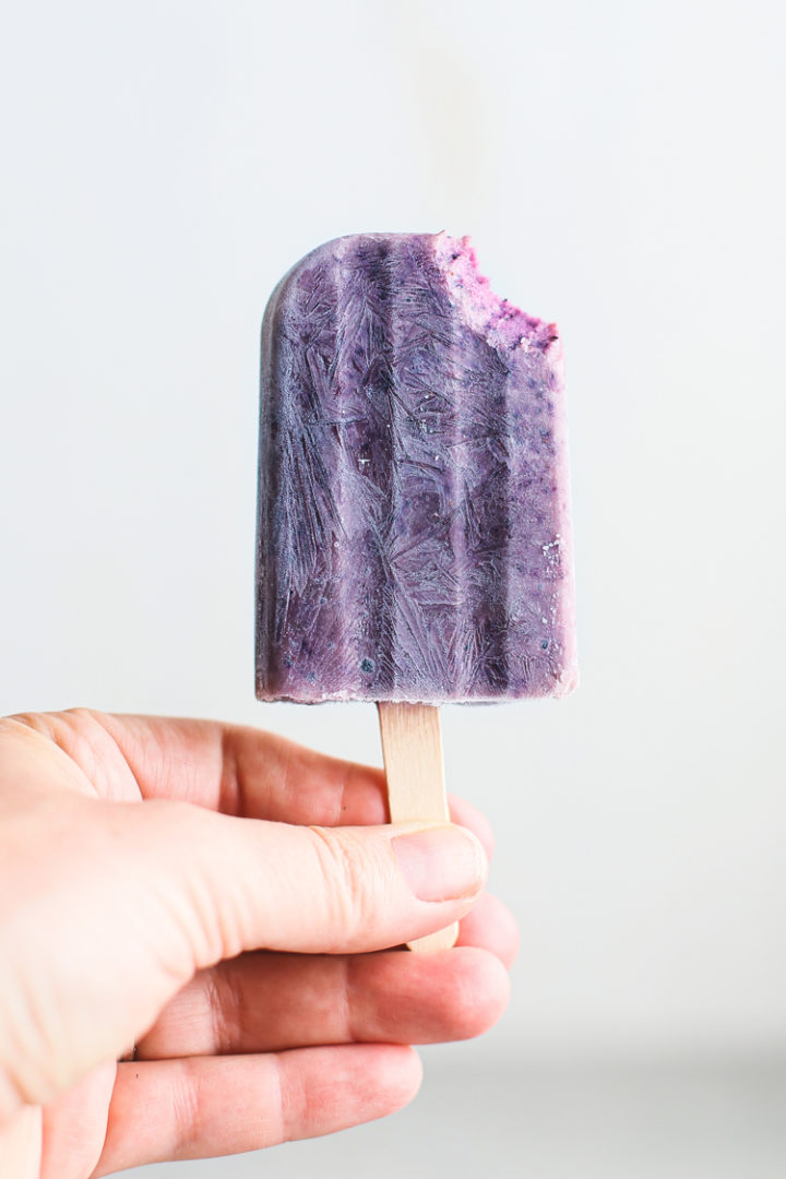woman holding a blueberry popsicle
