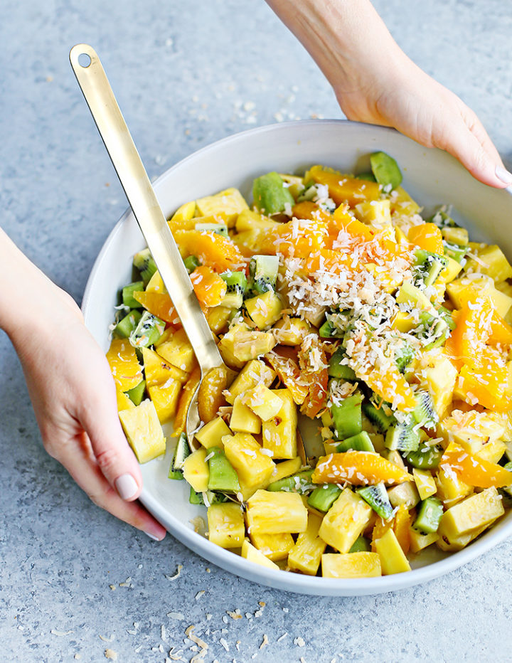 a photo of a woman holding a serving bowl of tropical fruit salad