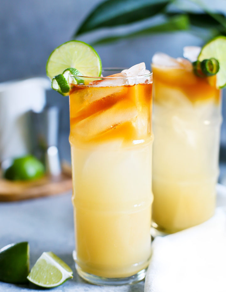 a close up photo of two tiki glasses with mai tai cocktails in them