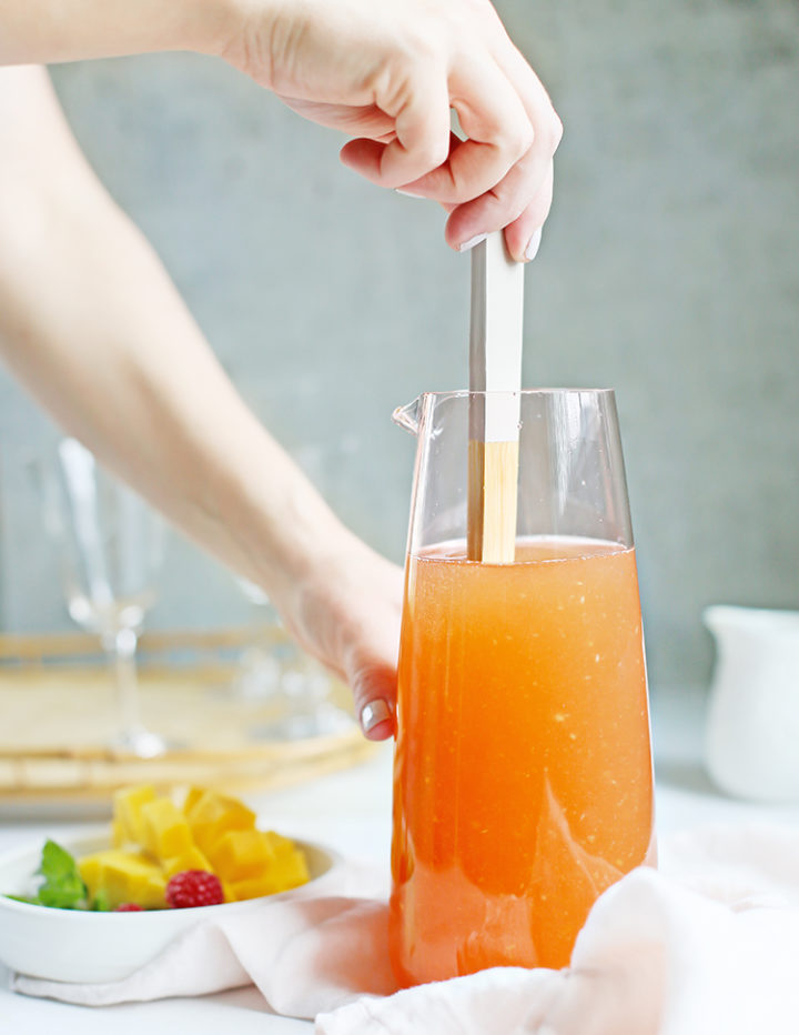 photo of a woman stirring rosé sangria with a wooden spoon