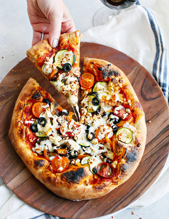 photo of woman picking up a slice of vegetarian pizza