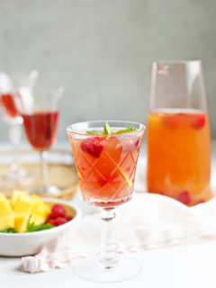 glasses of rosé sangria with a pitcher of raspberry mango sangria