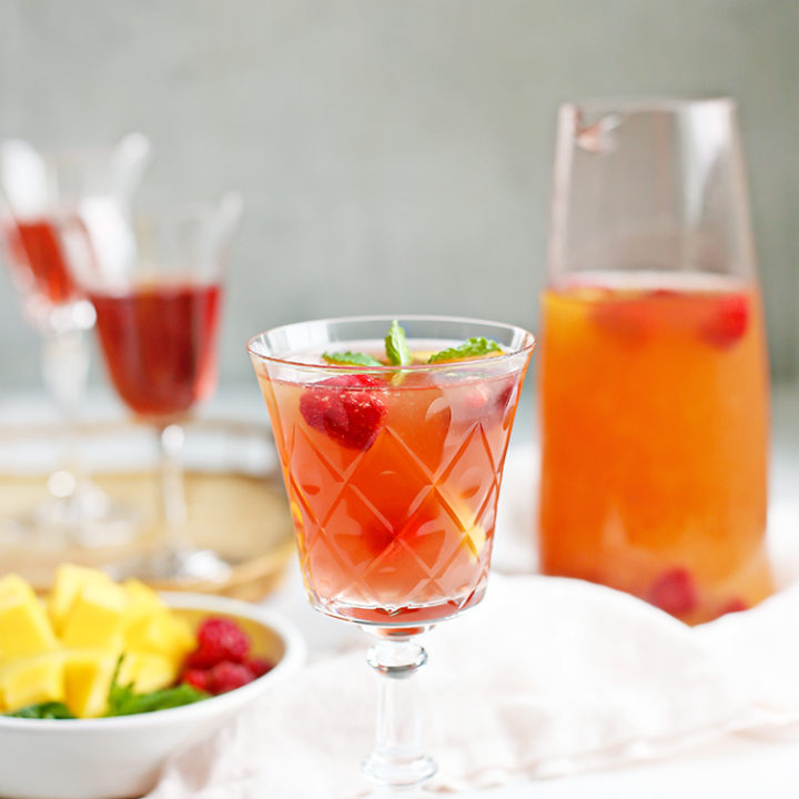 glasses of rosé sangria with a pitcher of raspberry mango sangria