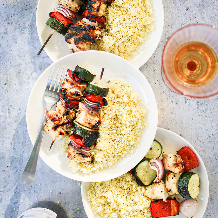 photo of grilled chicken kebabs on plates with couscous