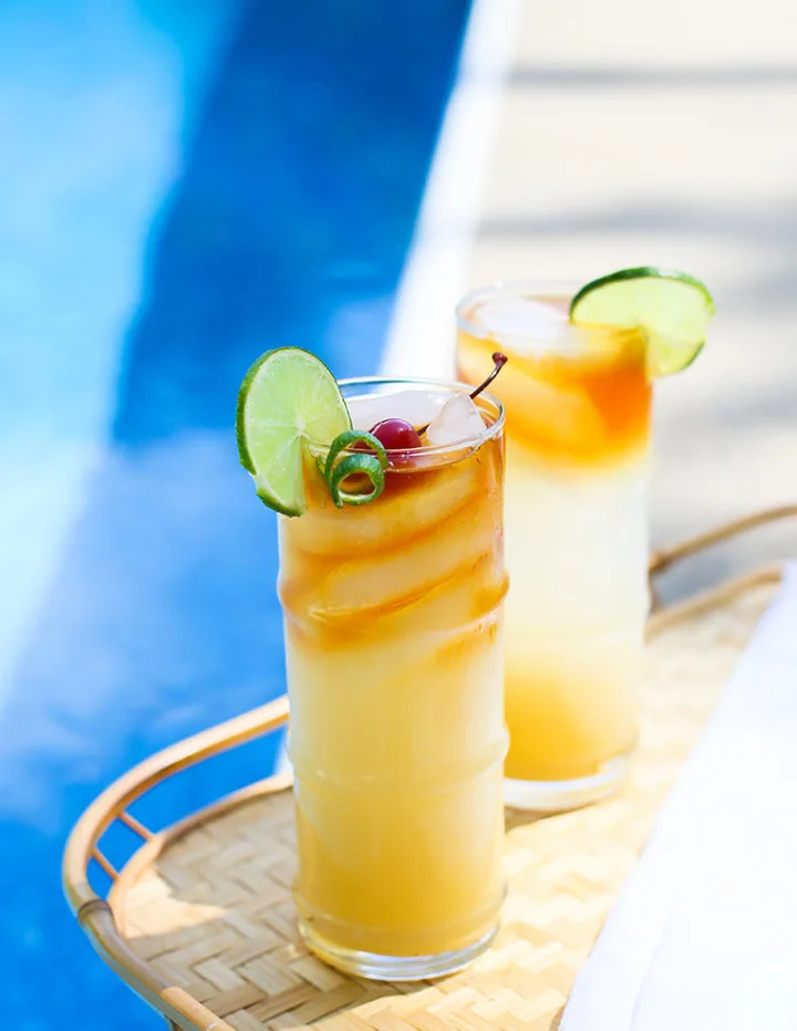 a photo of a tray by the pool with mai tai cocktails on it