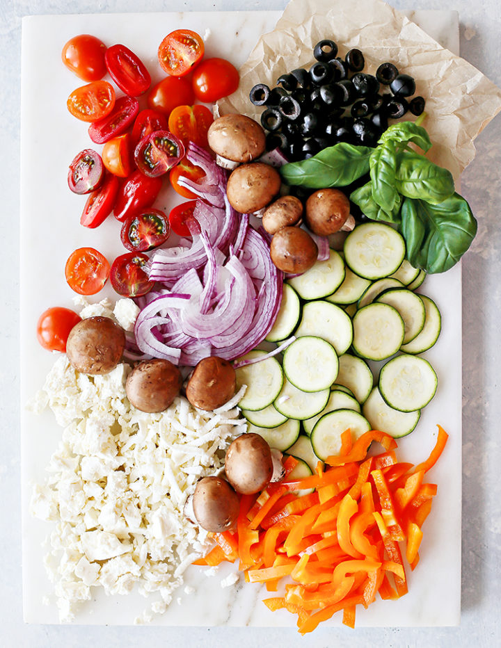 photo of veg pizza toppings on a white marble counter