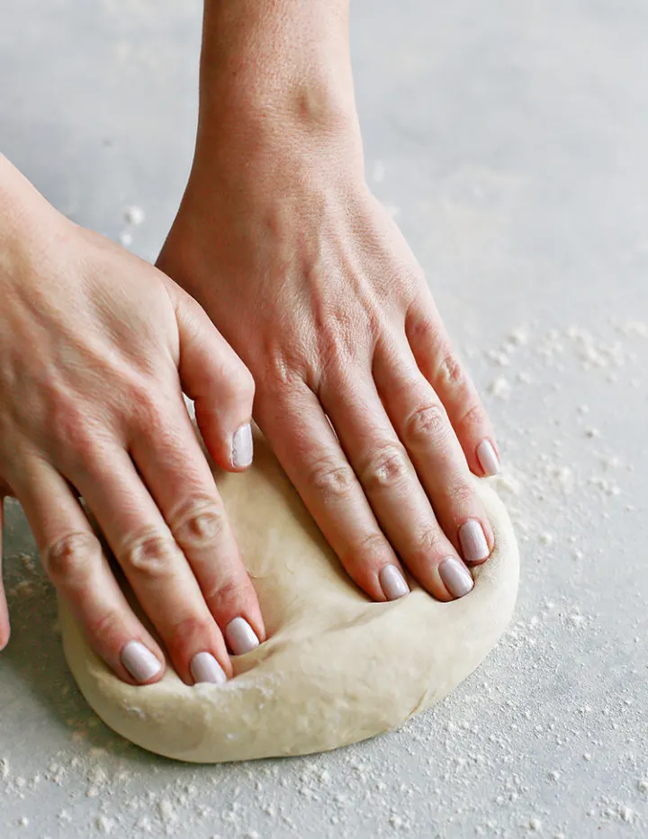 photo of woman kneading pizza dough for a vegetarian pizza recipe
