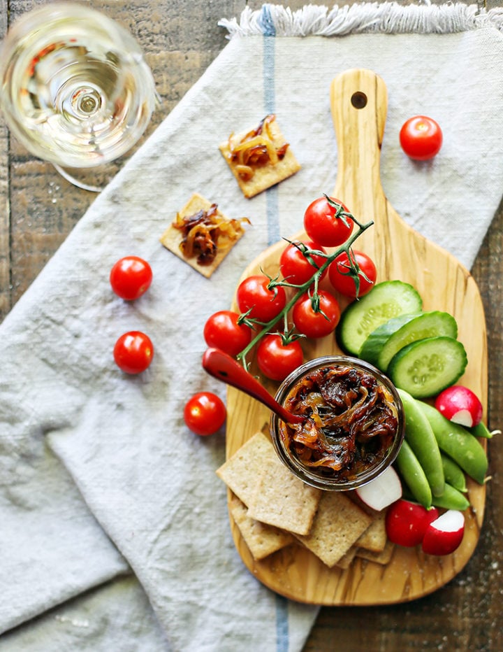 photo of a jar of caramelized onions with vegetables and crackers on a cutting board