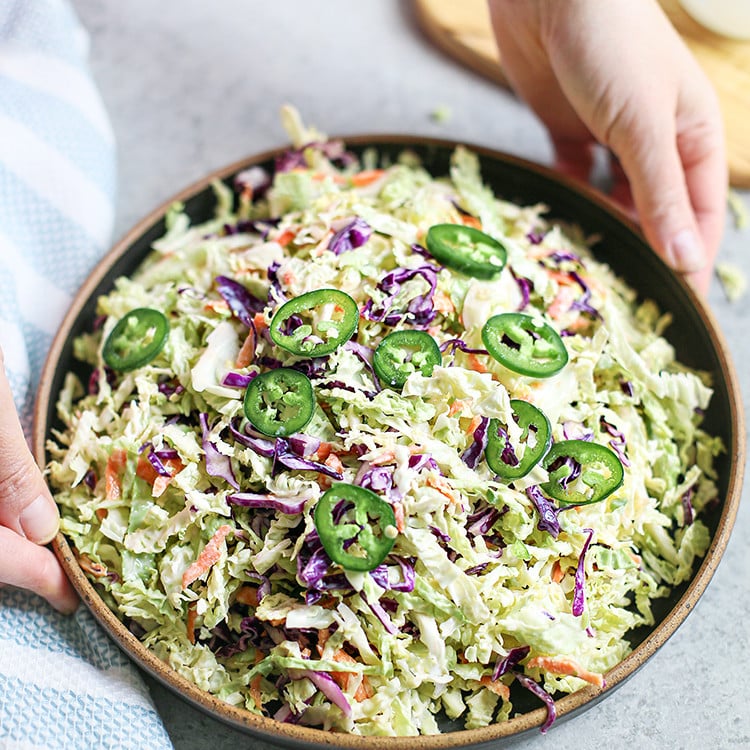 woman holding a bowl of jalapeño coleslaw