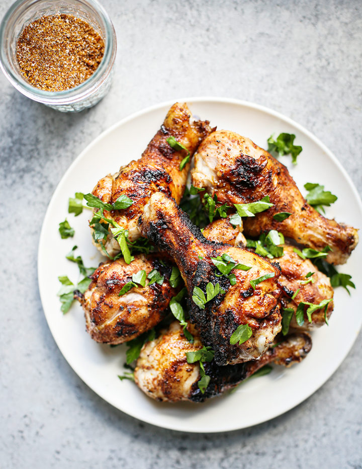 photo of chicken grilled with dry rub on a place with a jar of chicken rub next to it
