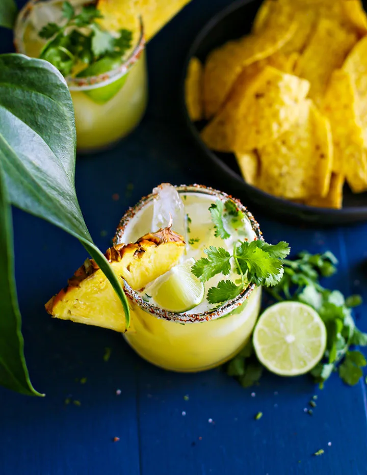 photo of a pineapple margarita with cilantro, lime, and pineapple garnish