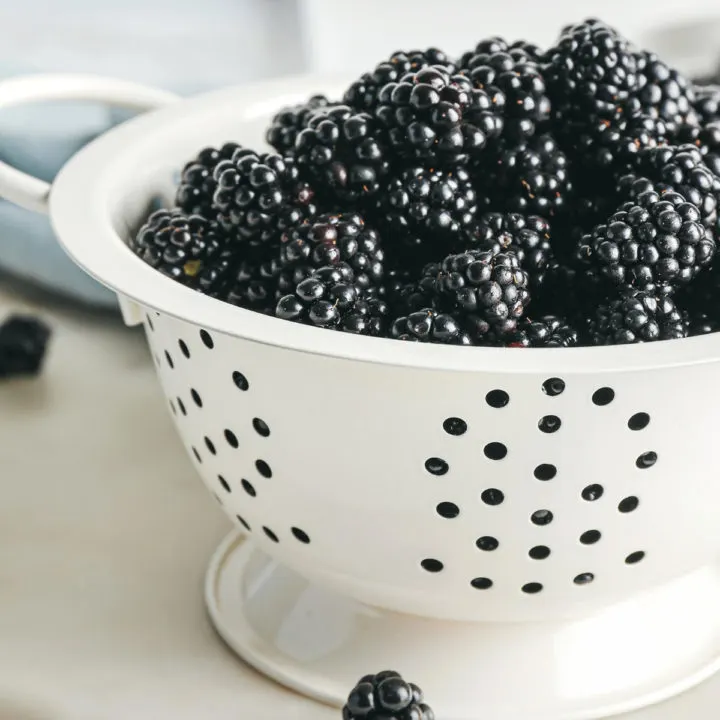 photo of fresh blackberries in a white colander for a tutorial on how to freeze blackberries