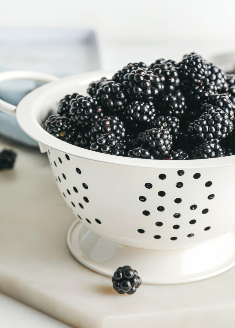 photo of fresh blackberries in a white colander for a tutorial on how to freeze blackberries