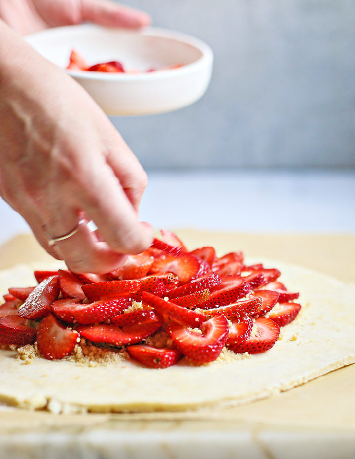 photo of woman adding strawberries to strawberry galette