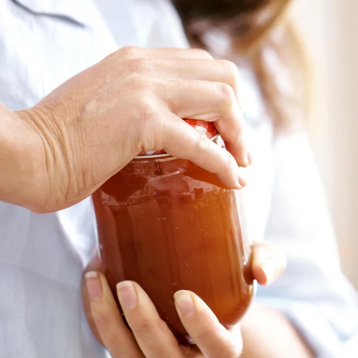 photo of a woman opening a jar with a tight lid