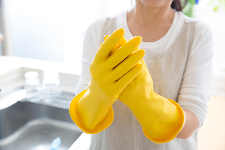 a photo of a woman wearing rubber gloves to explain how to open a jar using extra traction by wearing rubber gloves