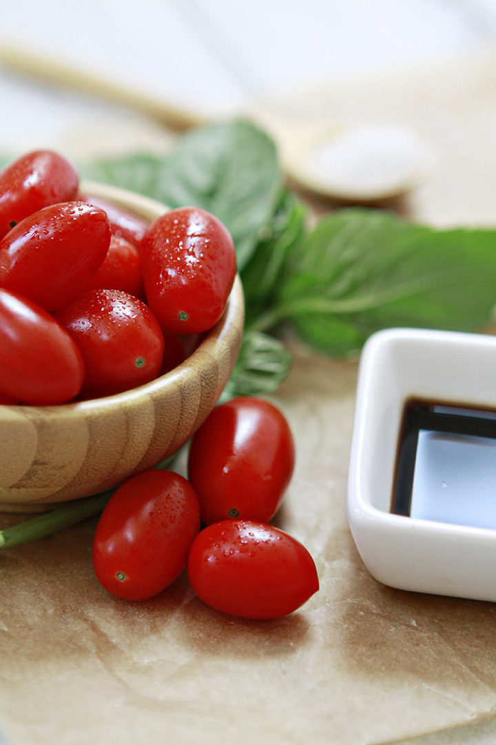 photo of grape tomatoes with basil and balsamic on a table for this pasta caprese recipe