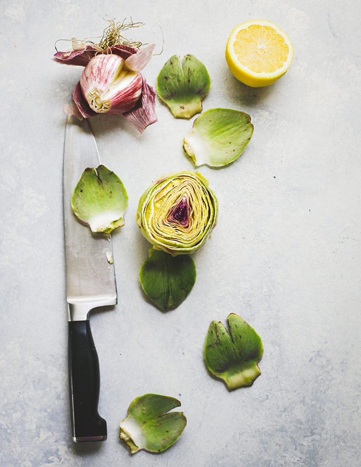 overhead photo demonstrating how to prepare baby artichokes for grilling