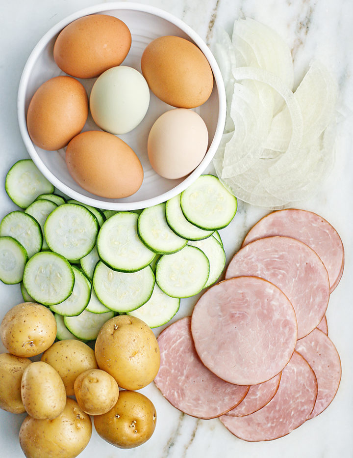 photo of zucchini, potatoes, canadian bacon, onion, and eggs for a zucchini frittata