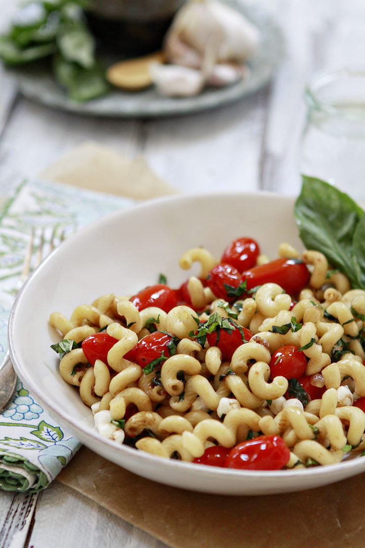 caprese pasta in a white pasta bowl with a fork and napkin