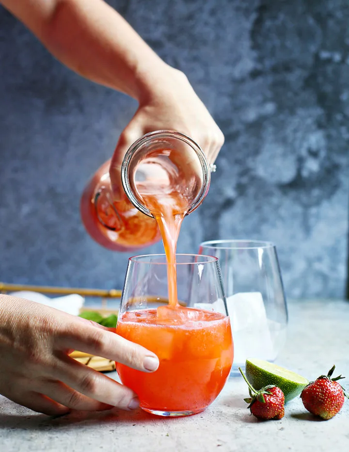 photo of woman pouring a glass of agua fresca