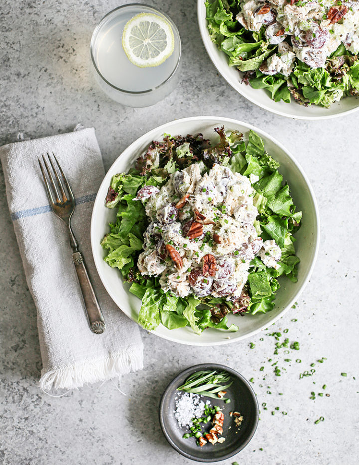 overhead photo of a table set with a bowl of greens with tarragon chicken salad on top, fork, and napkin