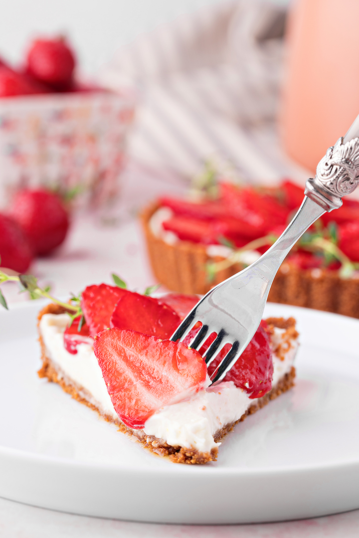 photo of a slice no-bake strawberry lemon tart on a white plate with a fork