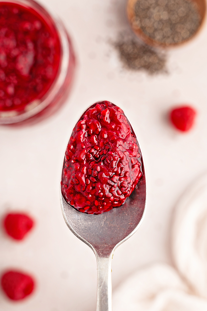 close up photo of raspberry jam on a spoon made from a chia jam recipe 