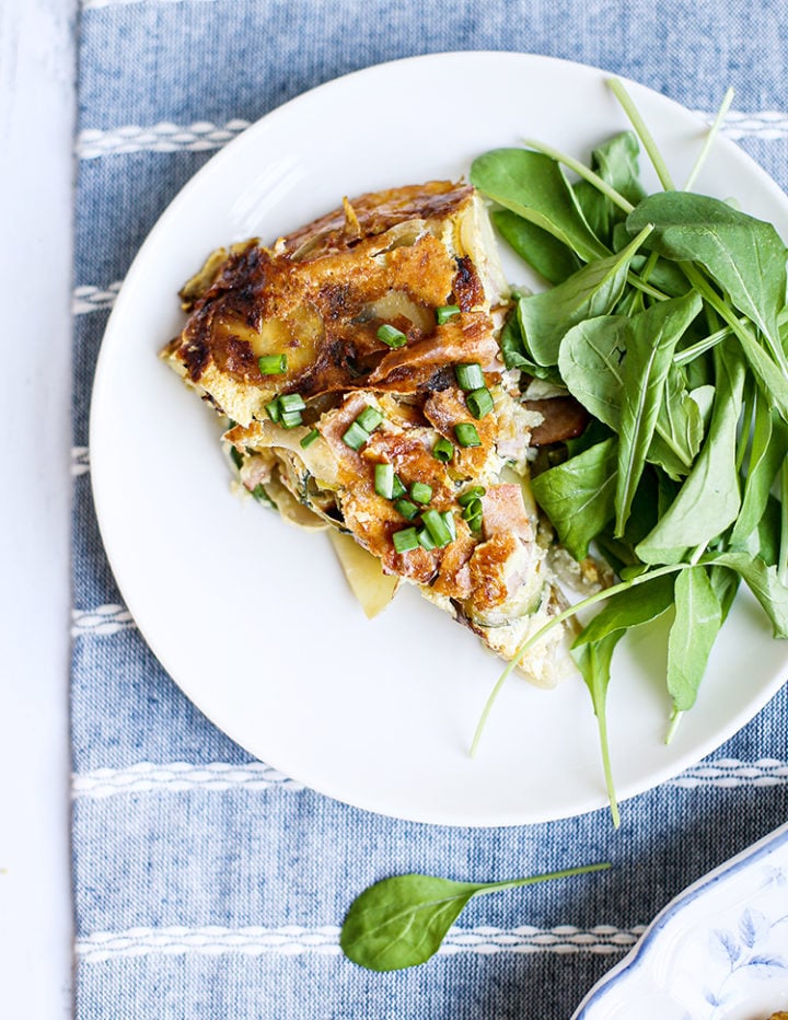 photo of a slice of zucchini frittata on a plate with a spinach salad