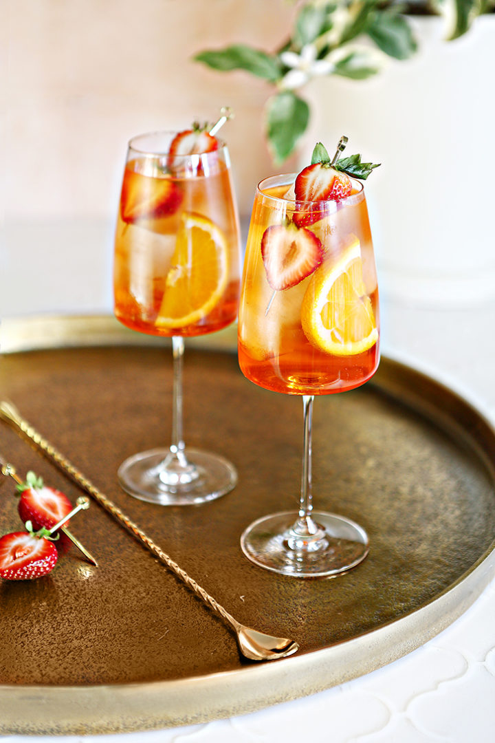 photo of 2 glasses of a strawberry aperol sprizt on a gold serving tray