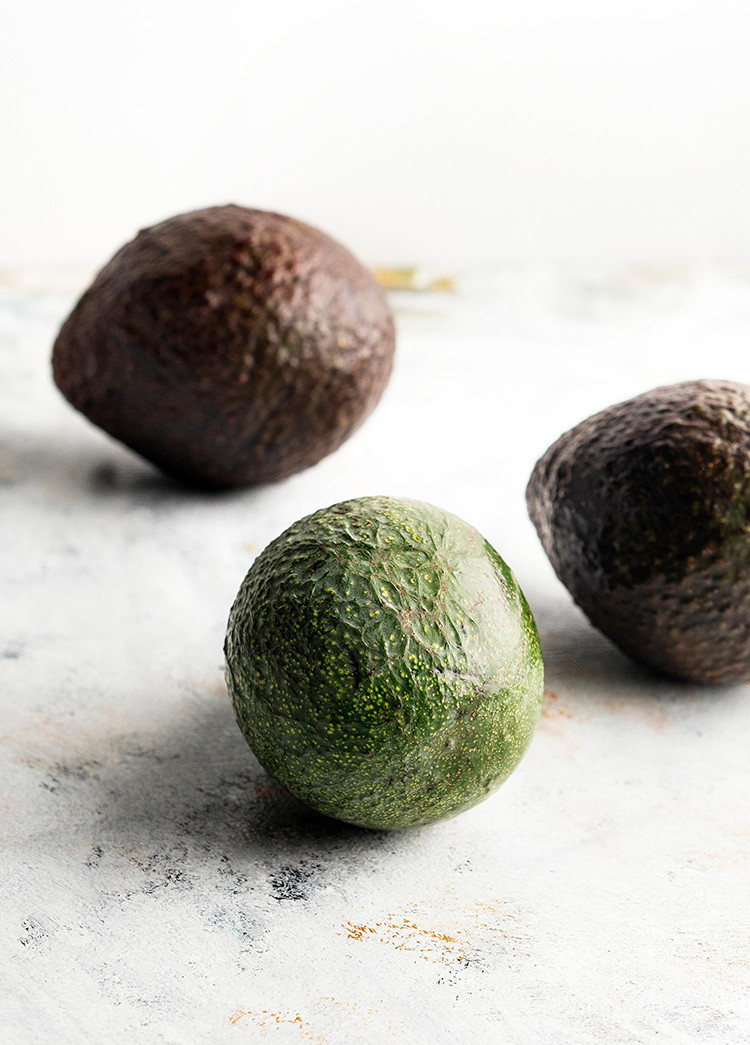 photo of avocados on a light surface for a tutorial on how to freeze avocados