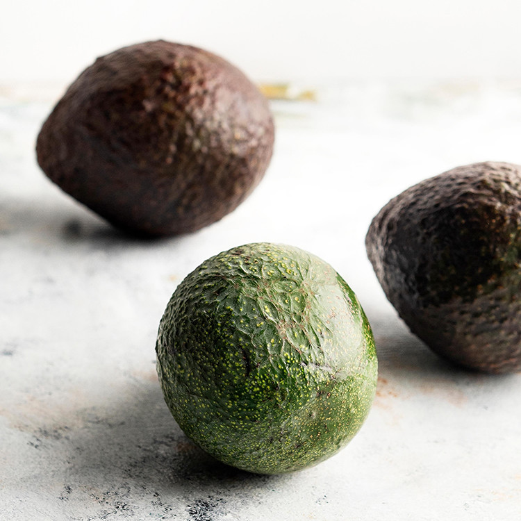 photo of avocados on a light surface for a tutorial on how to freeze avocados