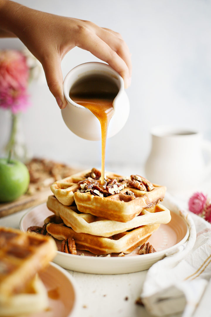 photo of apple cider syrup being poured on a stack of waffles