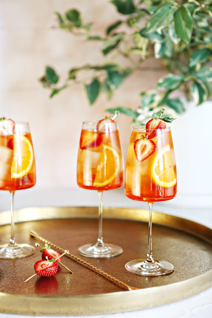 photo of 3 glasses of strawberry aperol spritz on a gold serving tray