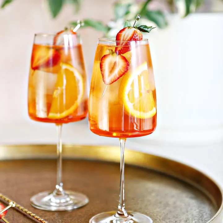 photo of two glasses of aperol spritz garnished with fresh strawberries and orange slices