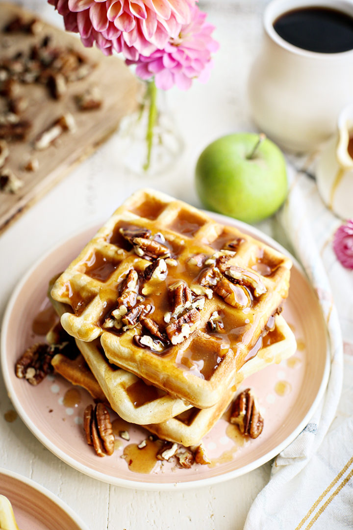 a stack of pecan waffles on a pink plate with syrup