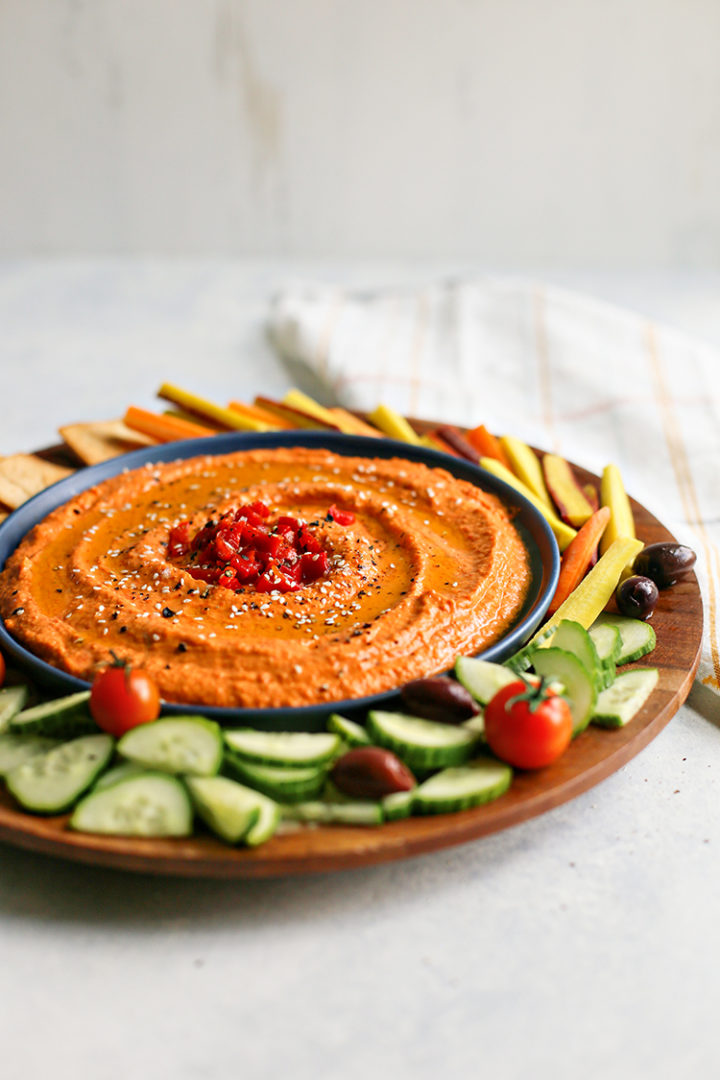 photo of red pepper hummus surrounded by vegetables