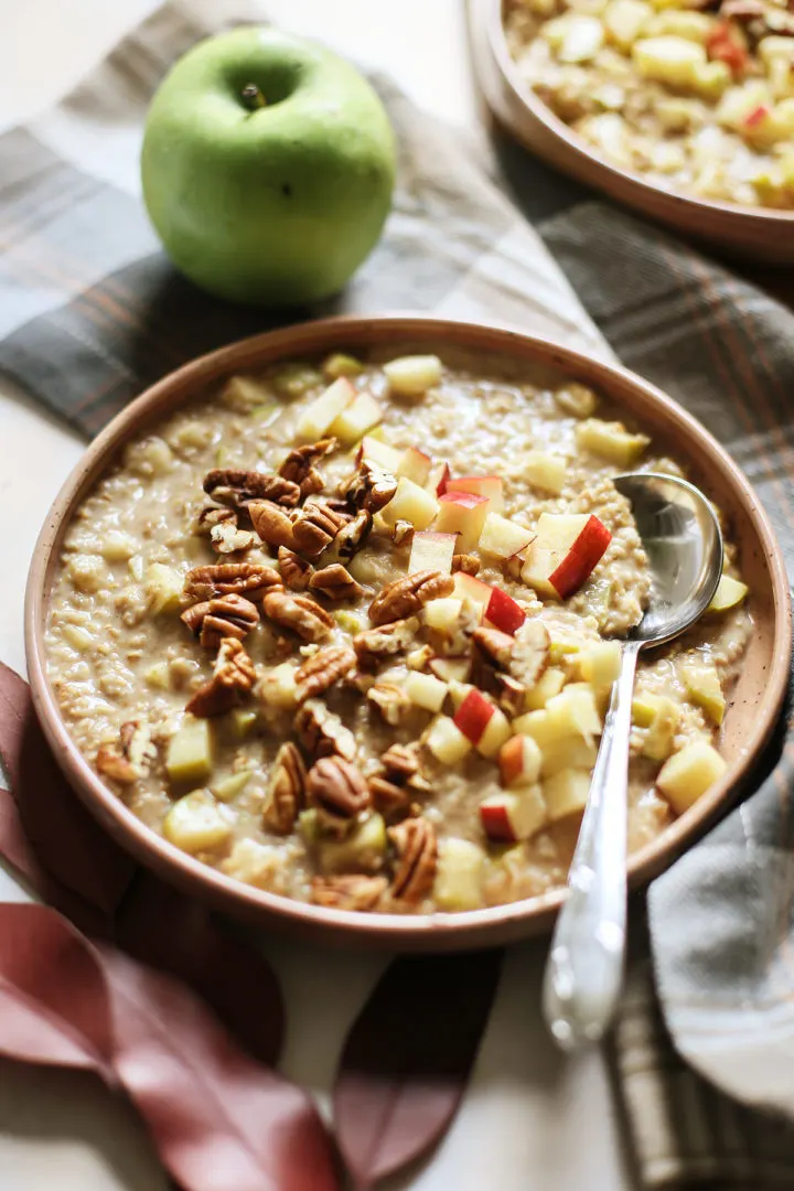 close up photo of a bowl of apple overnight oats with chopped apples and pecans on top