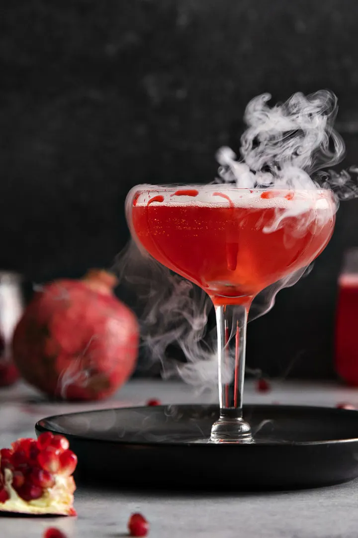 close up photo of a pomegranate halloween cocktail with dry ice