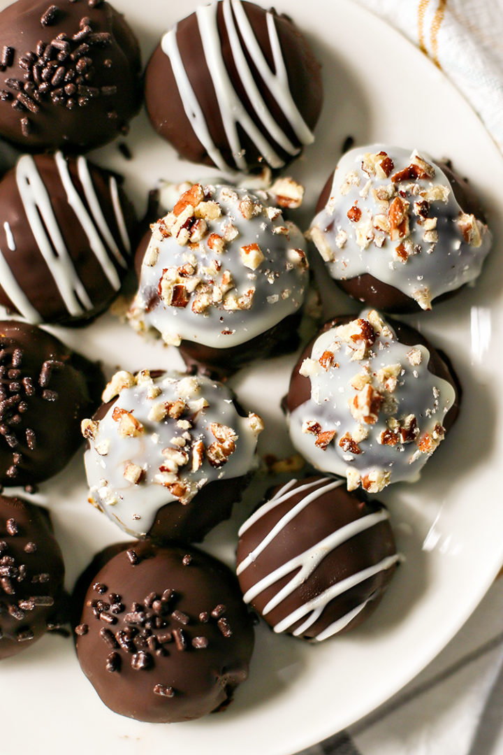 overhead photo of a plate of decorated chocolate coated pumpkin truffles