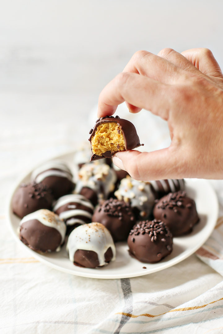 photo of woman holding a pumpkin truffle with a bite out of it showing the pumpkin filling center