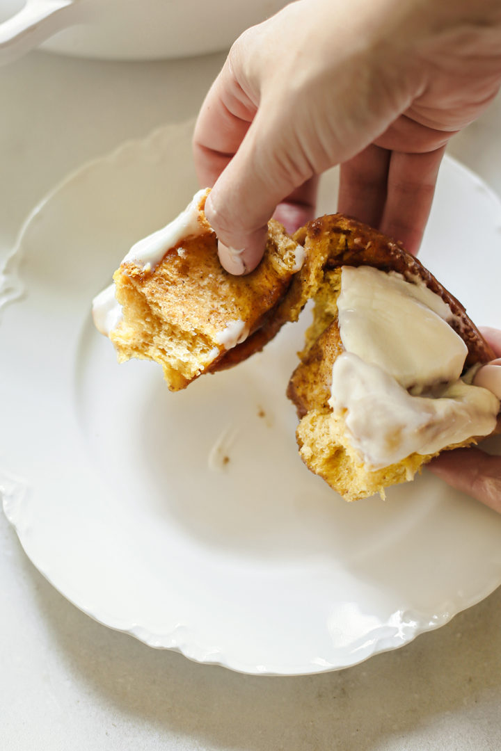 photo of a woman eating a pumpkin cinnamon roll