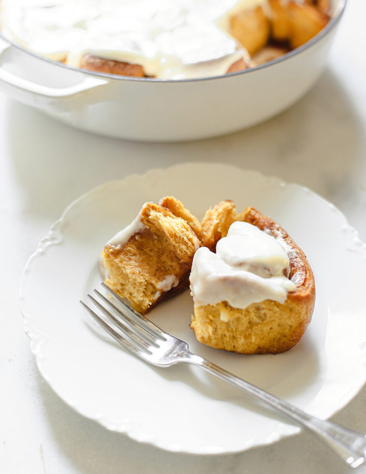 photo of a pumpkin cinnamon roll on a white plate with a fork