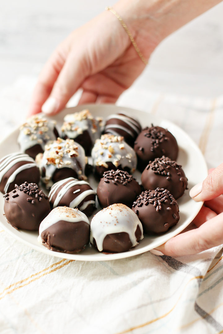 photo of woman holding a white plate full of chocolate covered pumpkin truffles